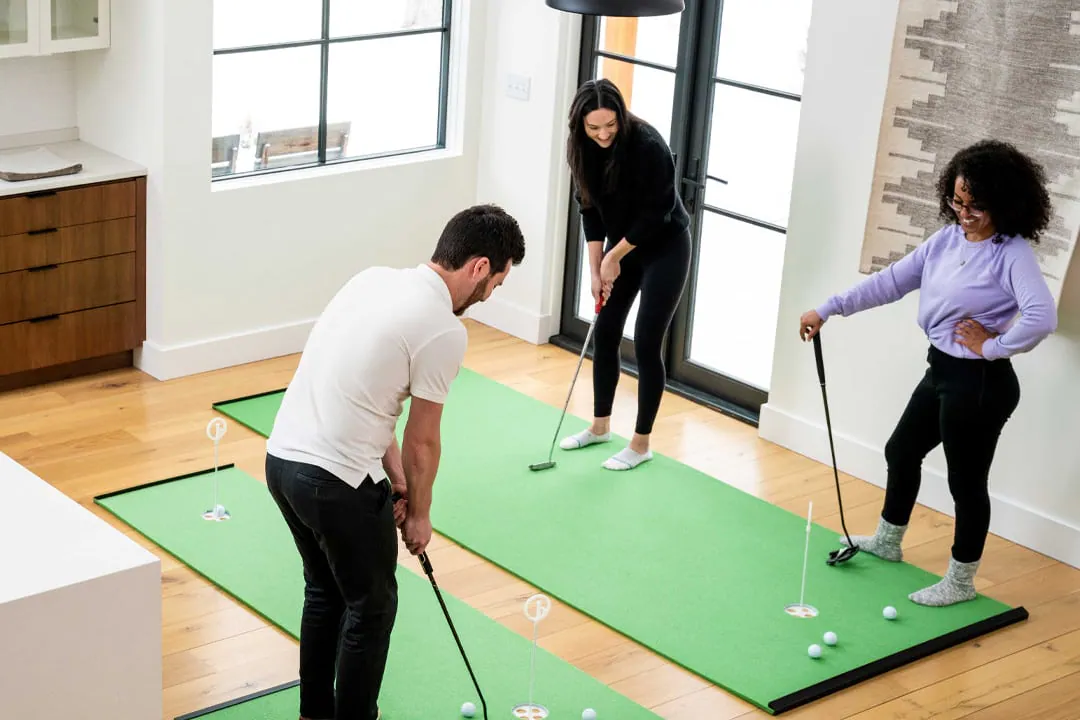 Three people practicing on BirdieBall indoor putting greens in a living room