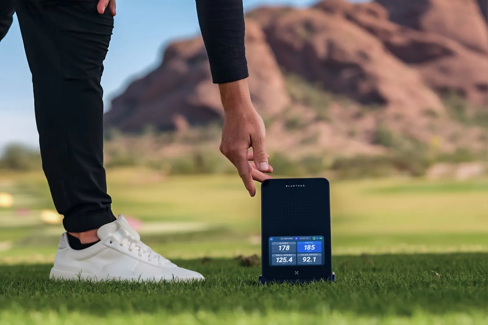 Golfer setting up a Blue Tees Rainmaker behind the ball outdoors