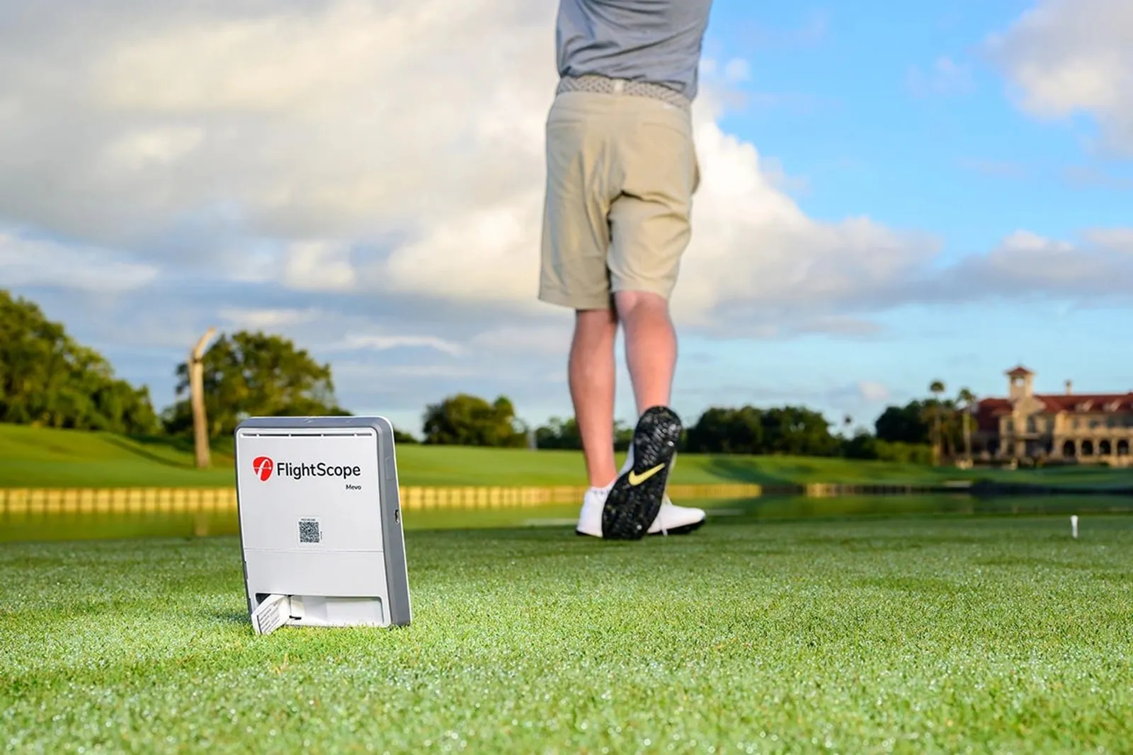 Golfer hitting driver outdoors with a FlightScope Mevo Gen2 behind him
