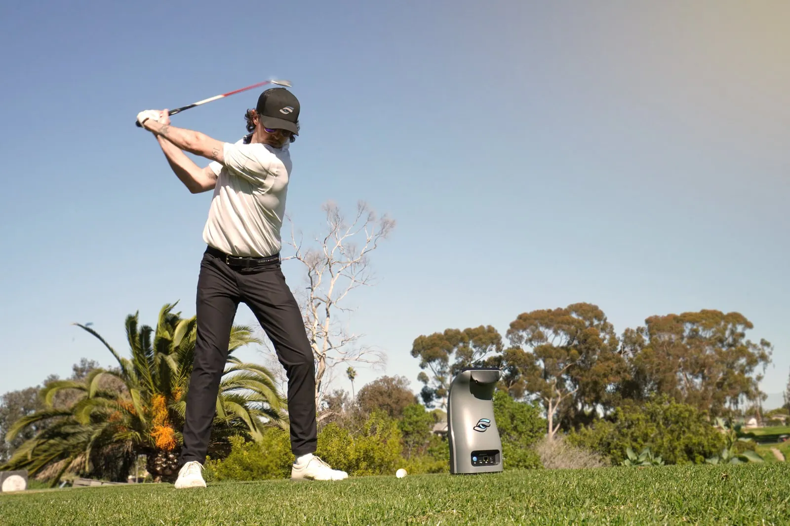 Golfer swinging on a range with a Foresight GC3 beside the ball