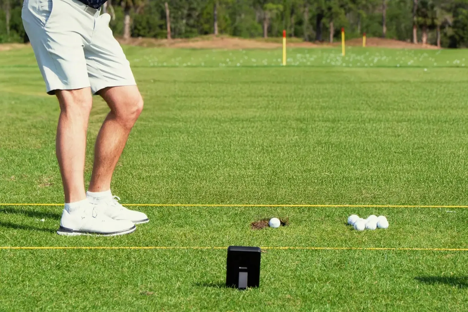 Golfer hitting with a Shot Scope LM1 behind the ball on a range