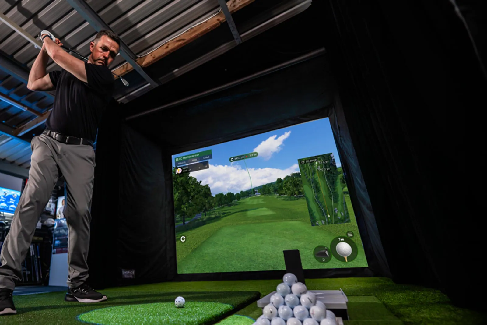 Golfer hitting in an indoor simulator with a Square Golf launch monitor