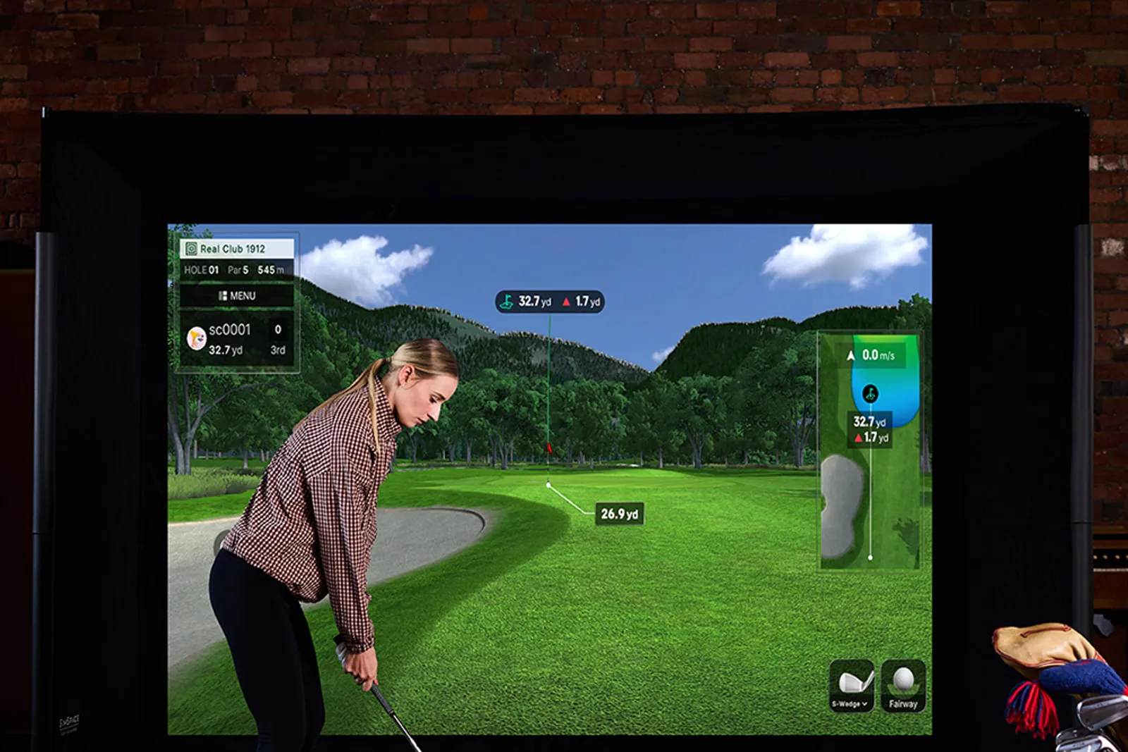 Golfer in a home simulator enclosure with a Square Golf Omni beside the ball