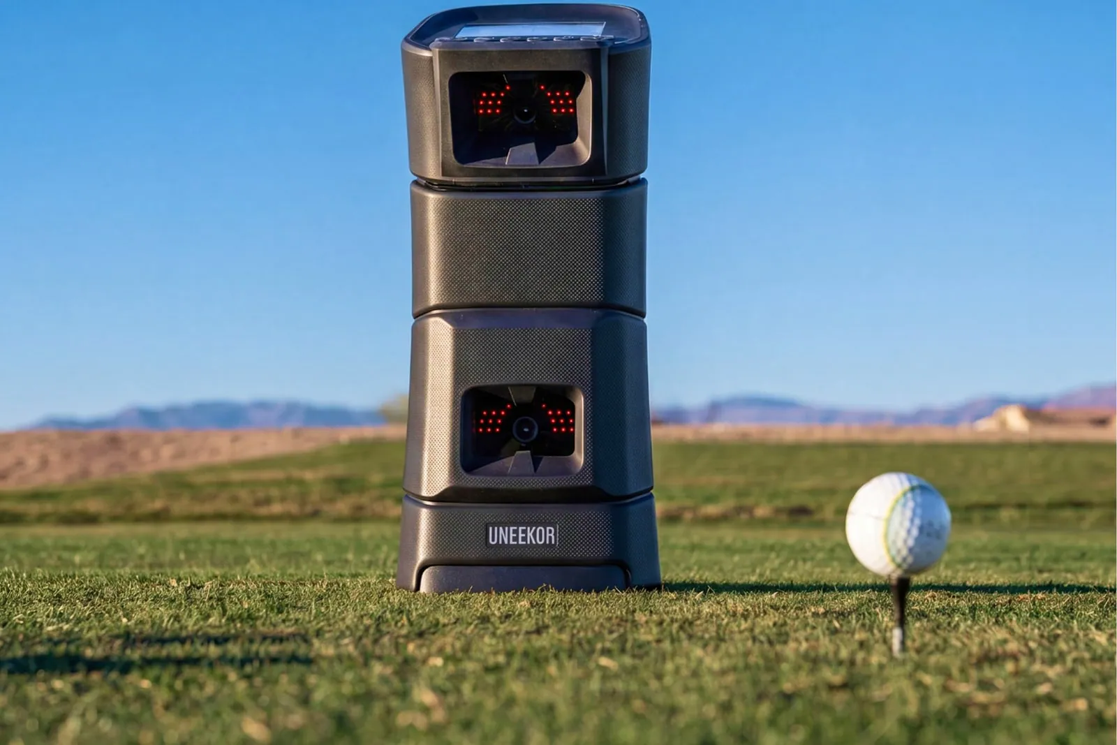 Uneekor EYE MINI beside a teed-up golf ball outdoors